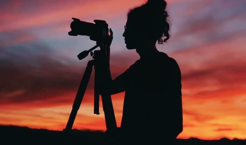 man holding a camera in under a sunset